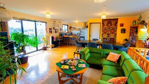 A spacious living room with a green sofa, a dining area, and a kitchen. - Retro Dunes - Wi-Fi. Linens. Fireplace. Pets OK (Venus Bay)