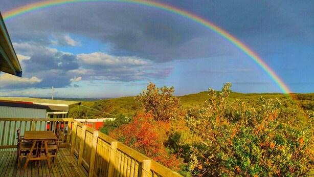 A wooden deck with a view of a landscape and a rainbow. - Retro Dunes - Wi-Fi. Linens. Fireplace. Pets OK (Venus Bay)