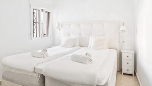 Ein heller Raum mit einem Bett, zwei Nachttischen und einer Wand-Klimaanlage.