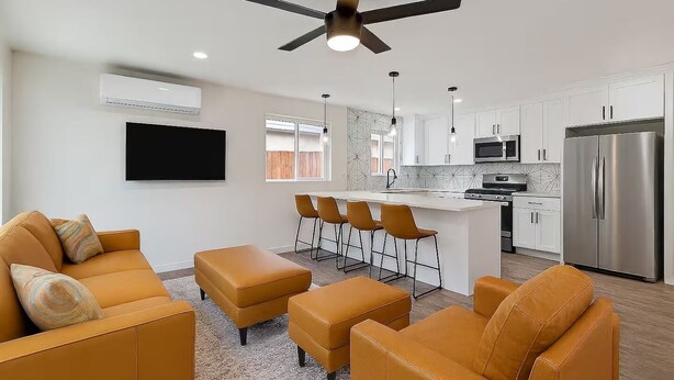 Una cocina moderna con armarios blancos, un refrigerador de acero inoxidable y una isla central con taburetes de bar.