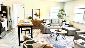 Een moderne woonkamer met een zithoek, een salontafel en een eethoek met een tafel en stoelen.