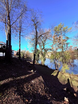 Ein Campingplatz am Seeufer mit Bäumen, einem Steg und einem Gebäude im Hintergrund.