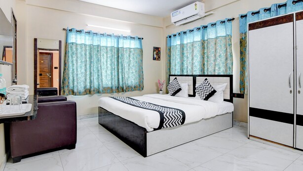 A hotel room with a bed, a desk, a wardrobe, and a ceiling fan. - Hotel Casa Inn (Baruipur)