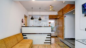 A modern interior with a sofa, a kitchen area, and a ceiling fan. - Hotel Casa Inn (Baruipur)