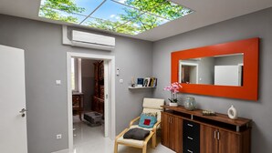 A modern interior with a skylight, a mirrored wall, a wooden cabinet, and a seating area.