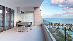 A modern balcony with a dining table and chairs, overlooking a pool and beach area. - Luxury Oceanview Retreat in Cancun 🌊 (Cancún)