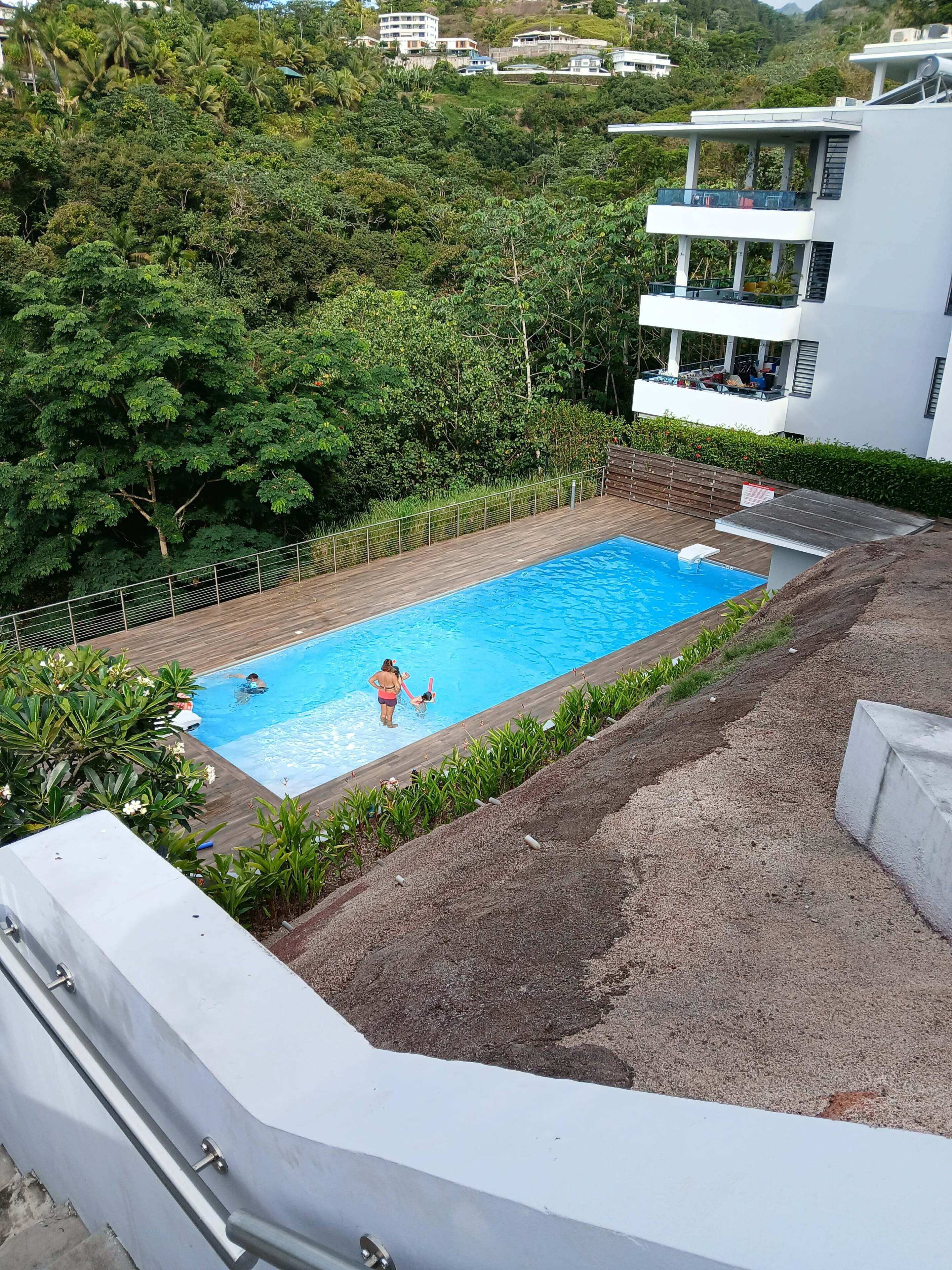 Una piscina circondata da una rigogliosa vegetazione, con un edificio moderno sullo sfondo.