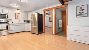 Una cocina moderna con armarios blancos, electrodomésticos de acero inoxidable y suelo de madera.