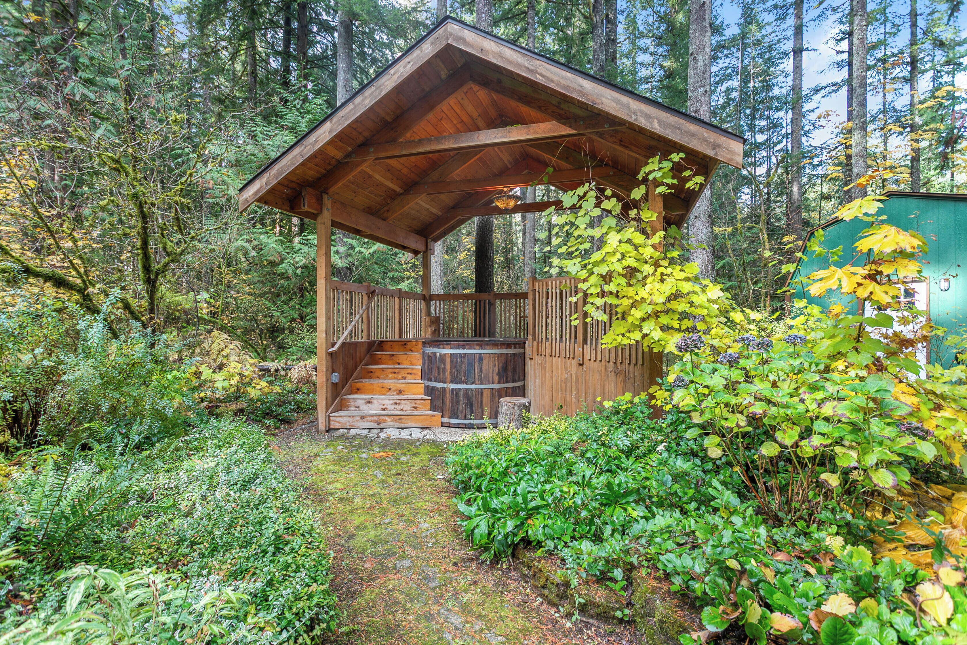 A wooden cabin with a porch and stairs leading up to it, surrounded by dense forest.