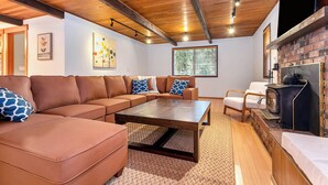 Una sala de estar acogedora con un sofá modular, una mesa de centro y una chimenea.