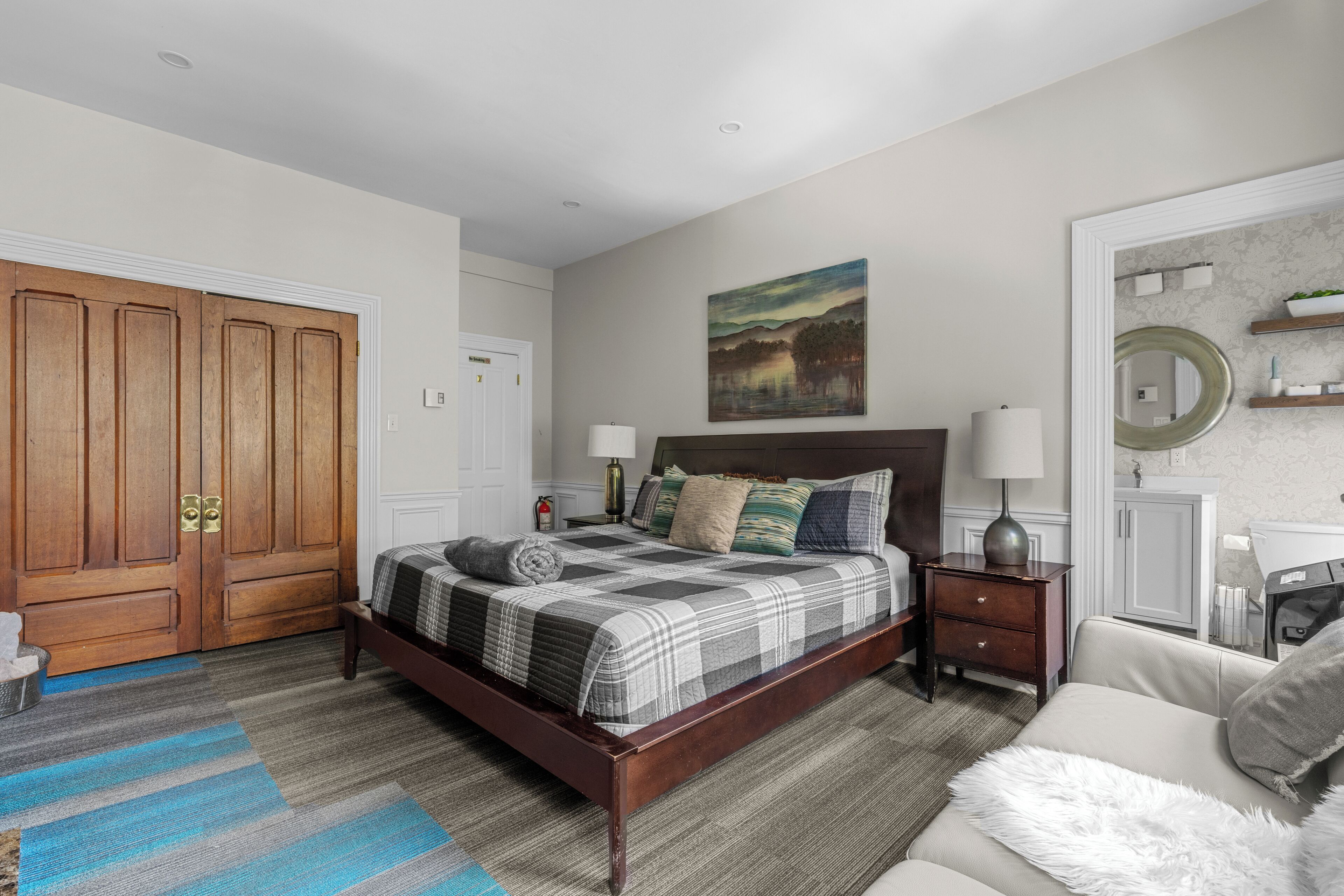 Quarto com cama de madeira, mesa de cabeceira, cómoda e um quadro na parede.