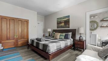Quarto com cama de madeira, mesa de cabeceira, cómoda e um quadro na parede.