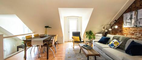 Un apartamento estilo loft con comedor, un sofá y una escalera que sube a un nivel superior.