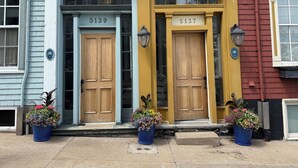 A row of three distinct buildings with numbered doors, each with a blue flower pot at the entrance. - Red George Inn and Suites (Halifax)