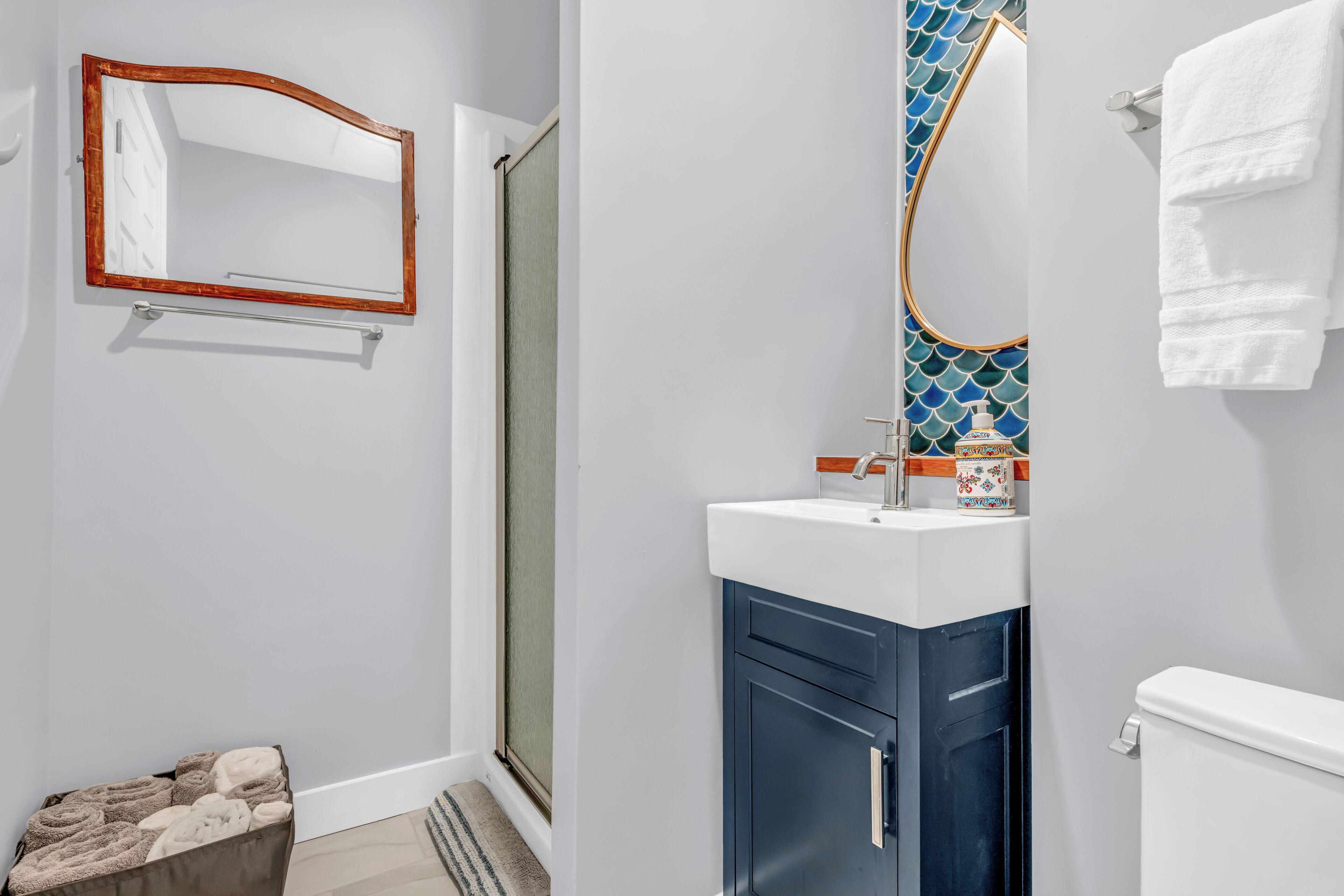 Une salle de bain équipée d’un miroir, d’un lavabo, de toilettes et d’un porte-serviettes.