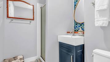 Une salle de bain équipée d’un miroir, d’un lavabo, de toilettes et d’un porte-serviettes.