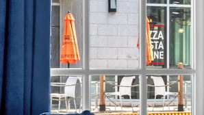 A window view of a restaurant with outdoor seating, a sign reading 'ZAZA STONE,' and a blue curtain partially covering the window. - Red George Inn and Suites (Halifax)