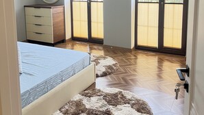 Een slaapkamer met een bed, een dressoir, een spiegel en uitzicht door grote schuifdeuren.