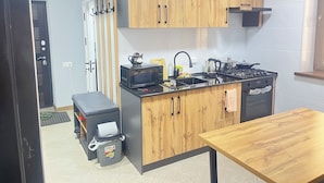 Een kleine keuken met houten kastjes, een gasfornuis, een magnetron en een spoelbak.