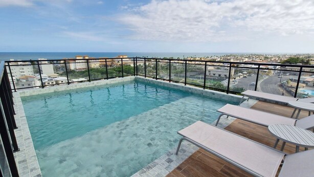 A rooftop infinity pool with clear water, surrounded by a glass railing and wooden deck. - COSTE0109 - Concept Life Stella (Salvador)