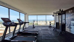 A gym with treadmills, a weight bench, and a wall-mounted TV. - COSTE0109 - Concept Life Stella (Salvador)