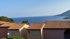 A coastal residential area with terracotta-roofed buildings, a clear sky, and the sea in the background. - Apartment 6 people sea view - Théoule sur mer (Côte d'Azur) - SAVANNAH (Théoule-sur-Mer)