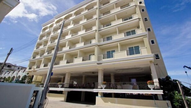 Un hôtel à plusieurs étages, doté de balcons à chaque niveau, d’un rez-de-chaussée couvert et, en arrière-plan, d’un ciel dégagé.