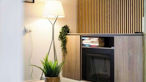 Ein modernes Interieur mit Stehlampe, Blumentopf, Kamin und Bücherregal.