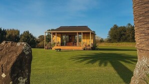 A house with a porch, a lawn, and a palm tree. - Allure- Your Auckland Wellbeing Getaway (Hobsonville)
