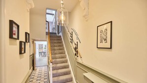A staircase with a patterned floor, a chandelier, and framed artwork on the walls. - Host Stay Hextol Retreat (Hexham)