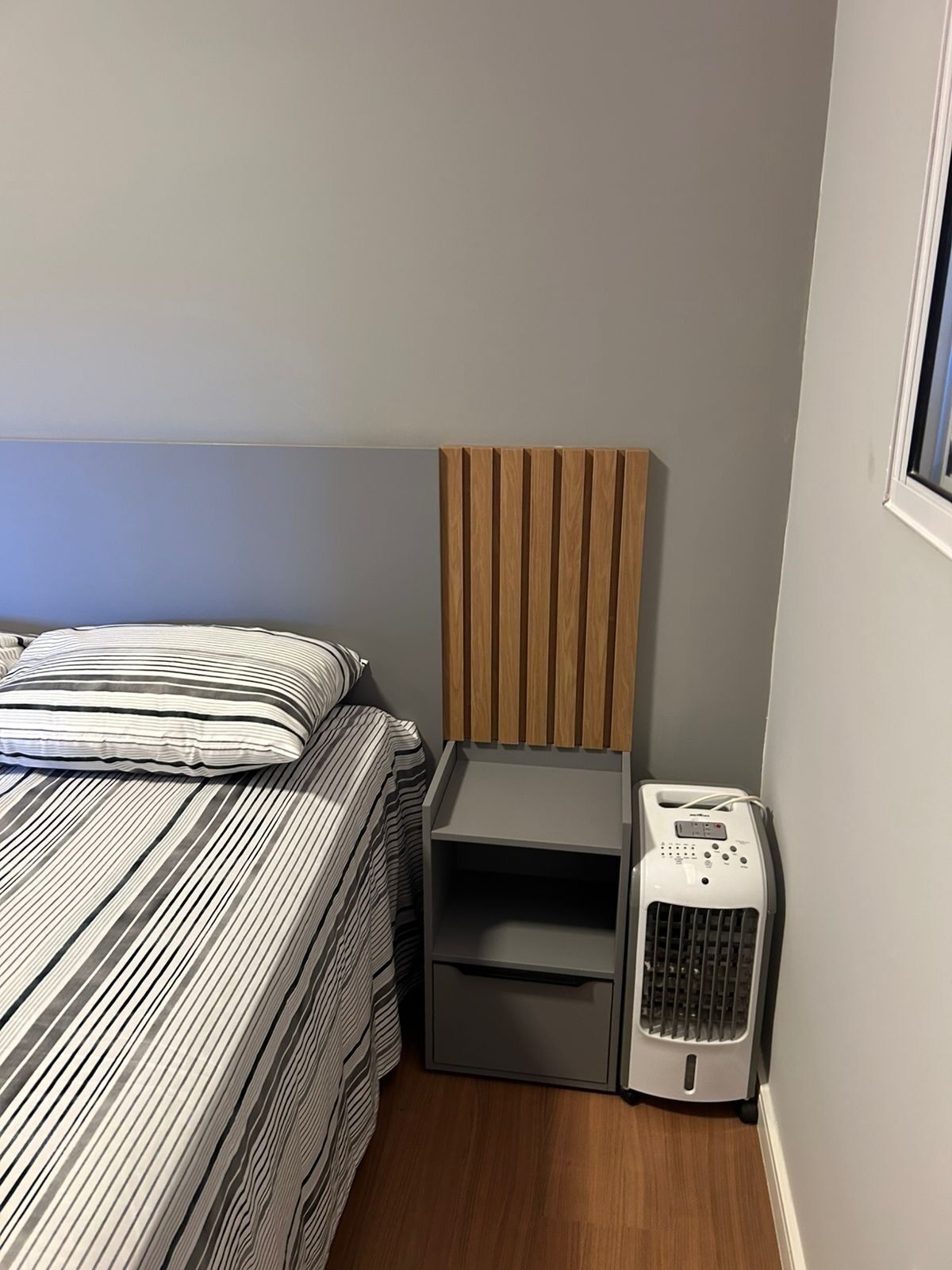 Un dormitorio con una cama, una mesita de noche y un calefactor portátil.