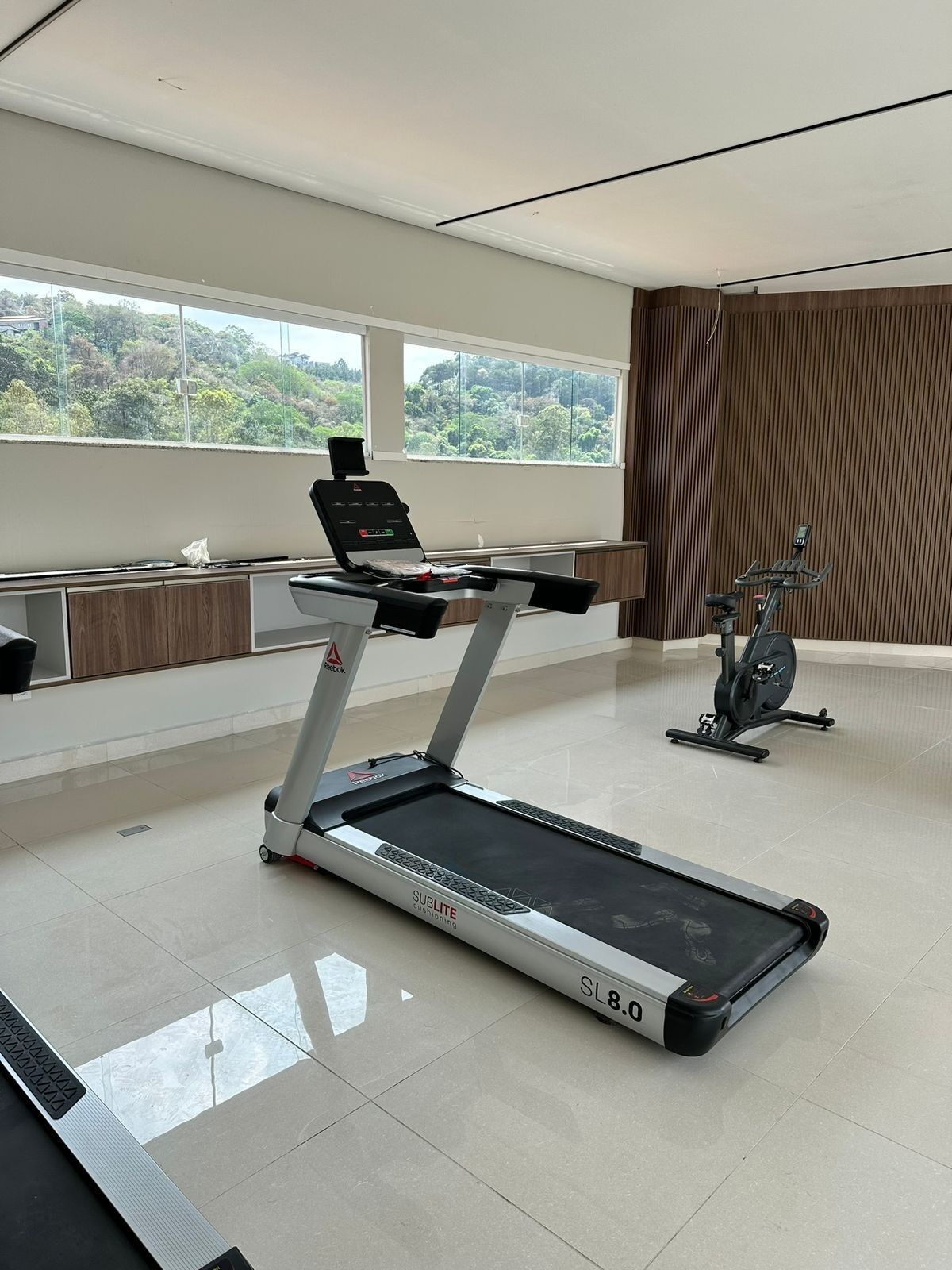 Un gimnasio moderno con cinta de correr, elíptica y un espacio de escritorio.