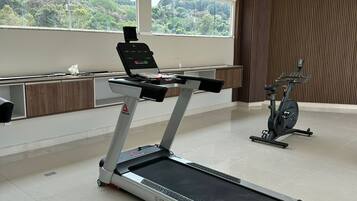 Un gimnasio moderno con cinta de correr, elíptica y un espacio de escritorio.