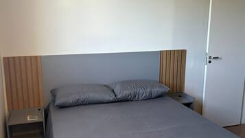 Un dormitorio con una cama individual, una mesita de noche, un cabecero de madera y una puerta.