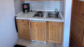 A compact kitchen with wooden cabinets, a stove, a sink, and a coffee maker. - Fackler Apartments 1 Riederstein - Relaxed Bavarian Living Near Lake Tegernsee (Tegernsee)