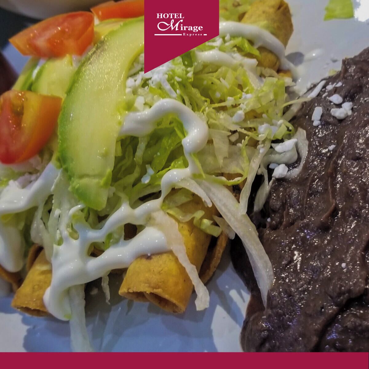 A plate of nachos topped with avocado, lettuce, and a white sauce, accompanied by a serving of black beans.
