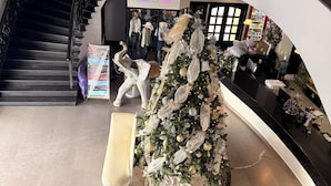 A grand staircase with a chandelier, a Christmas tree, and mannequins in the background. - Hotel Mirage Express (Matamoros)