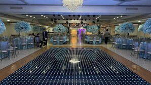 A spacious hall with a central stage, rows of tables with chairs, and a patterned floor. - Hotel Mirage Express (Matamoros)