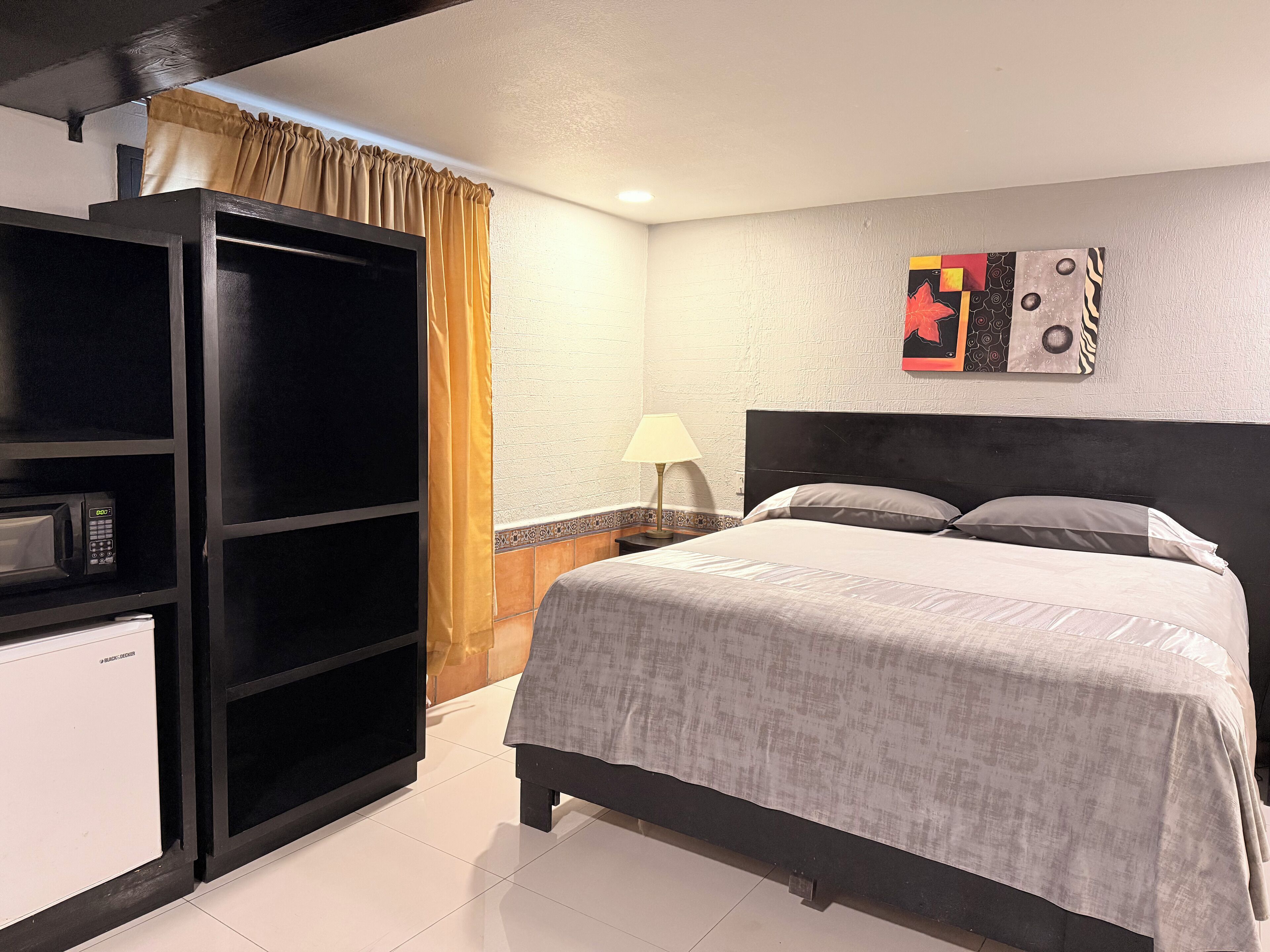 Une chambre d’hôtel équipée d’un lit, d’une armoire, d’un four à micro-ondes et d’une œuvre d’art murale.