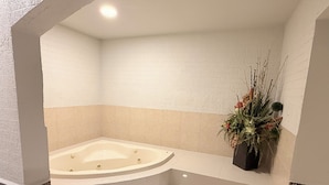 A bathroom with a freestanding bathtub, a step-up design, and a decorative plant. - Hotel Mirage Express (Matamoros)