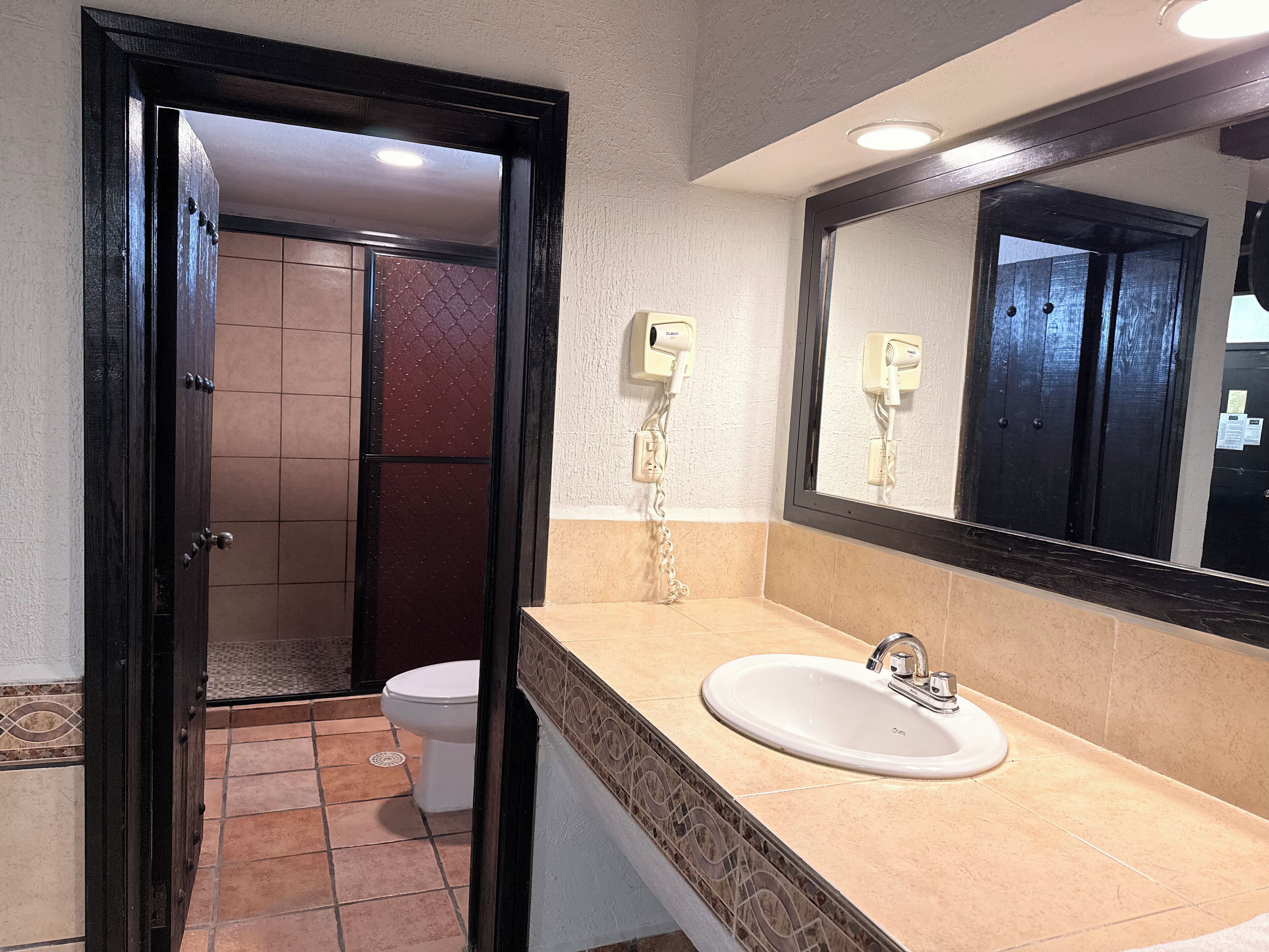A bathroom with a toilet, sink, and mirror.