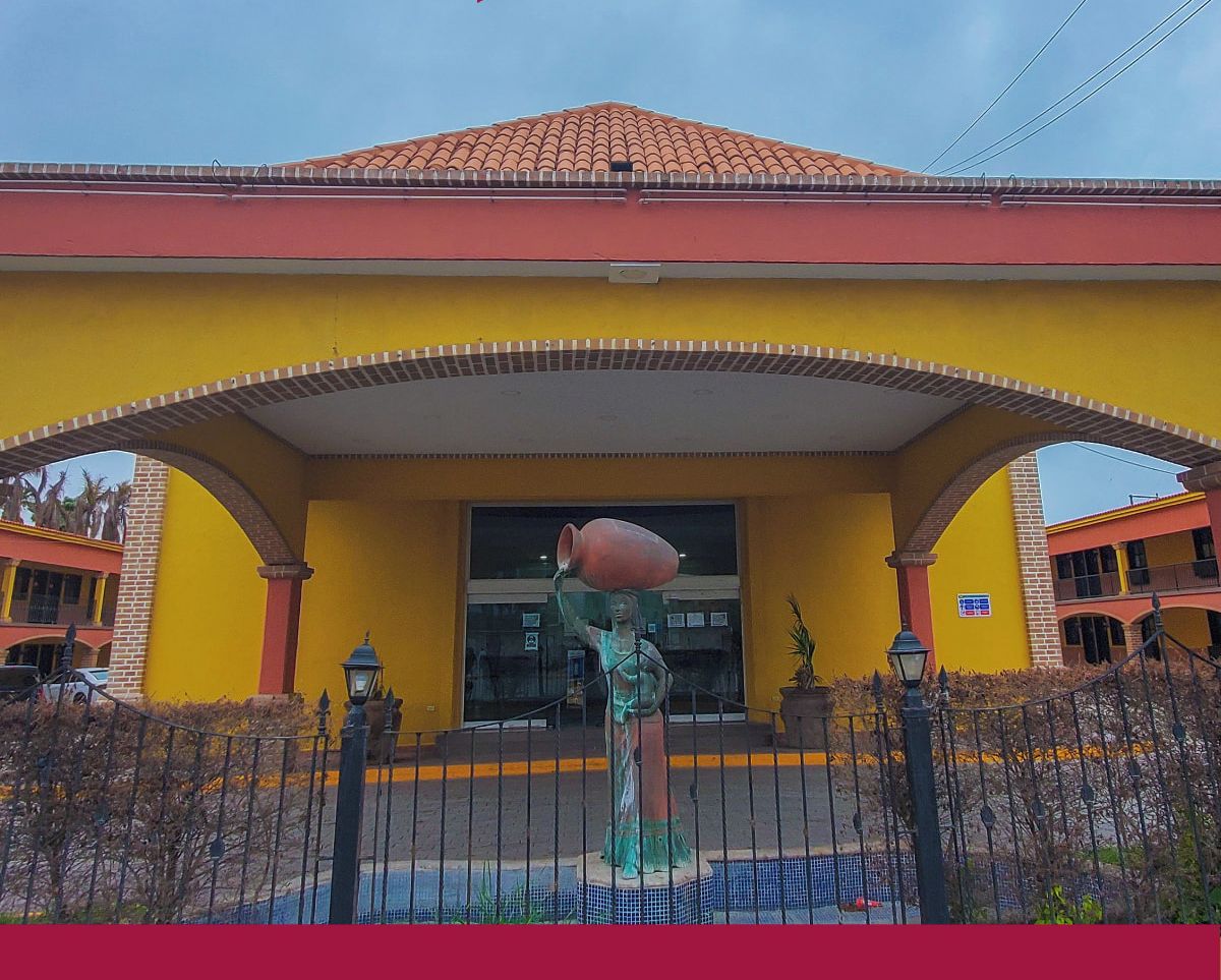 Un edificio amarillo con techo rojo y una estatua en su fachada.
