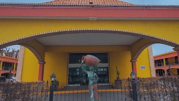 Un edificio amarillo con techo rojo y una estatua en su fachada.