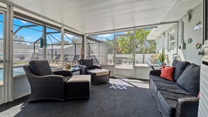 A covered outdoor area with wicker furniture, a pool, and a view of the surrounding area. - The Getaway (Spring Hill)