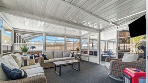 A covered patio area with wicker furniture, a coffee table, and a red heater. - The Getaway (Spring Hill)