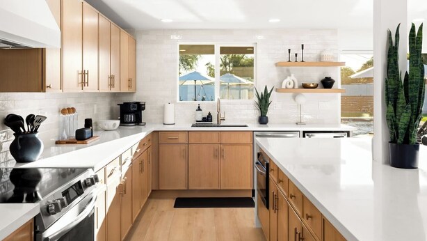 Una cocina moderna con armarios de madera, una estufa de acero inoxidable y un amplio ventanal con vistas al exterior.