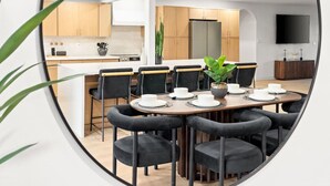 Un comedor moderno con una mesa redonda, sillas negras y una planta en maceta.