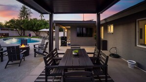 Un patio cubierto con piscina, mobiliario exterior y un televisor de pantalla plana.