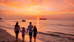Tramonto sull'oceano con una famiglia che passeggia sulla spiaggia.