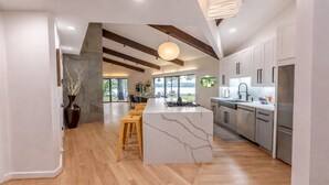 A modern kitchen with a large island, wooden flooring, and a view of a lake.